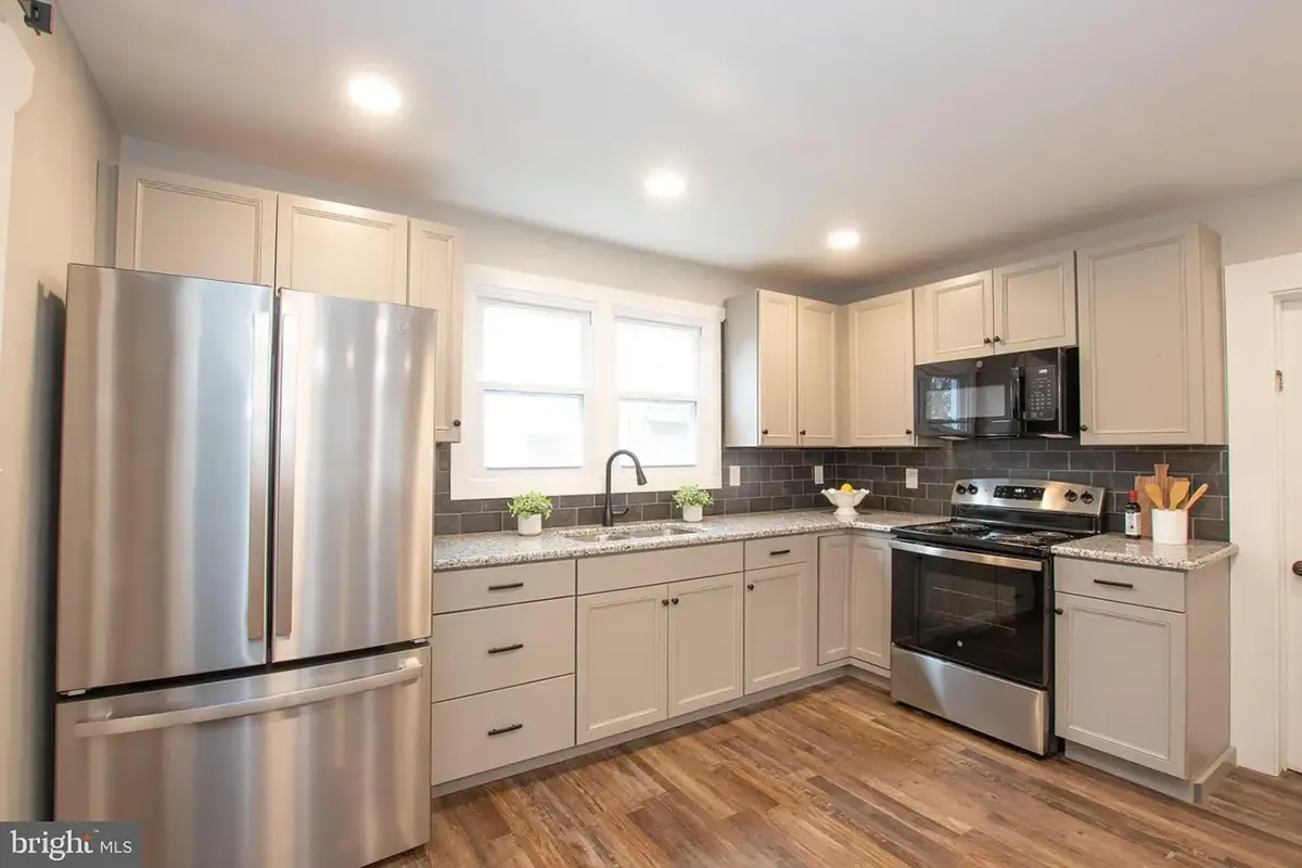 Kitchen with stainless appliances, white cabinets and large window.