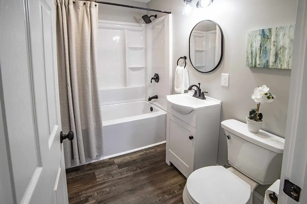 Light and bright bathroom with white vanity and wood floors.