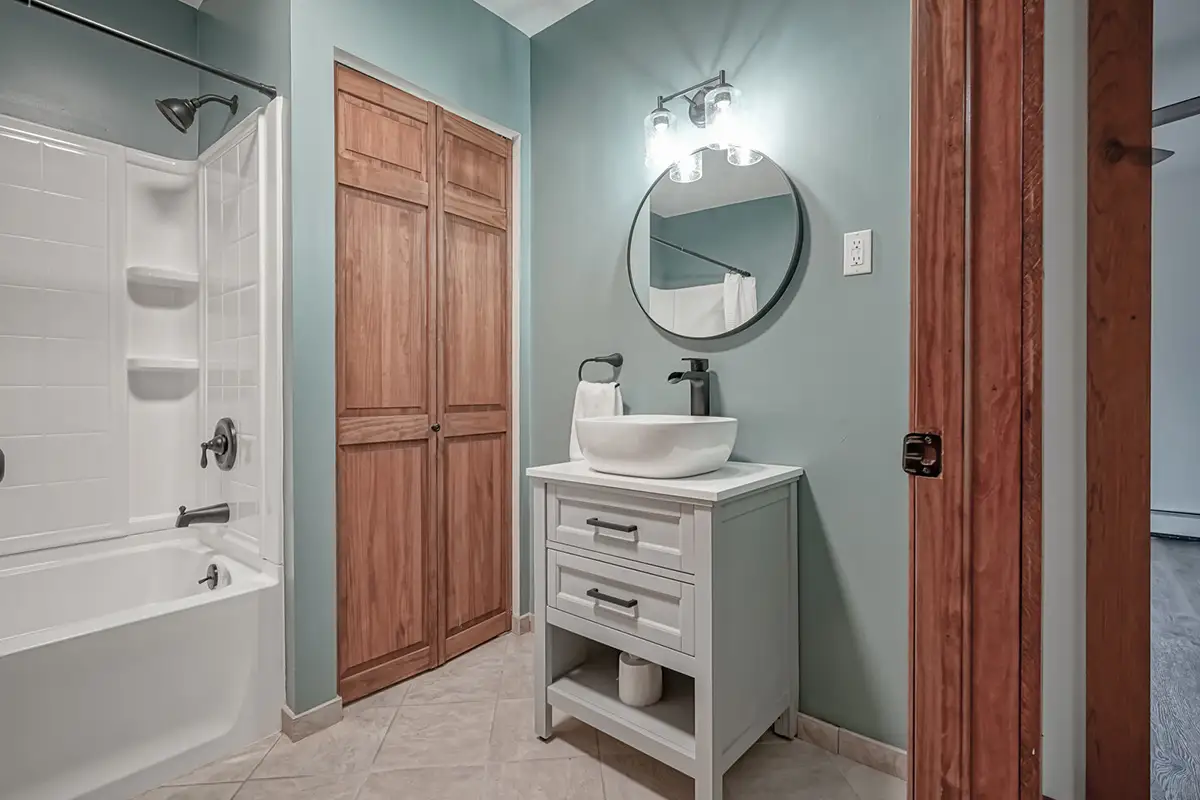 Second bathroom with light green gray walls and vanity.