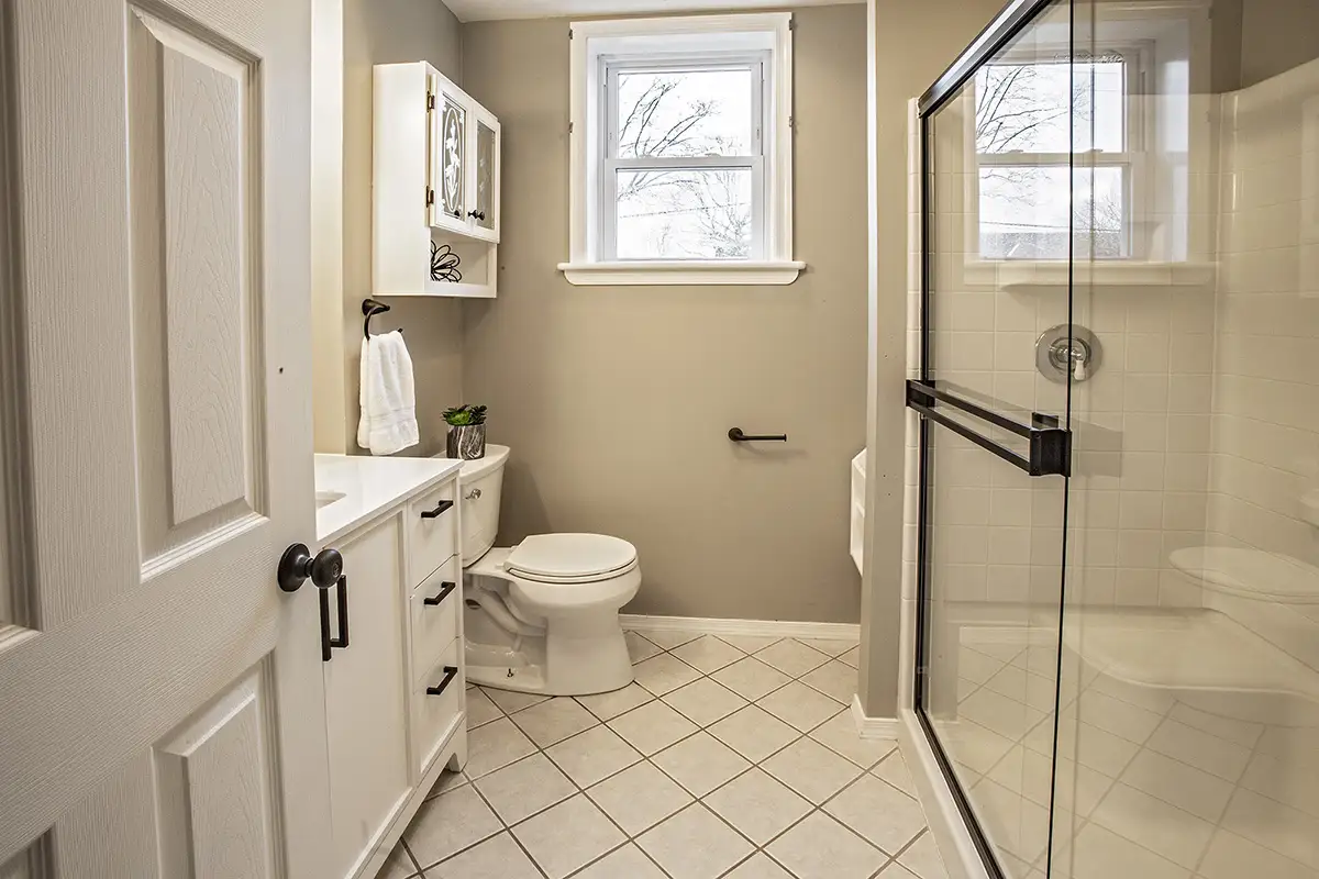 Beige bathroom with glass door shower and tile floor.